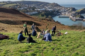 A group of people congregating together on a coastal cliff top.