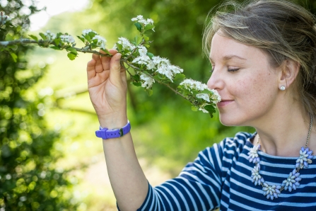 Woman in her garden smelling a flower