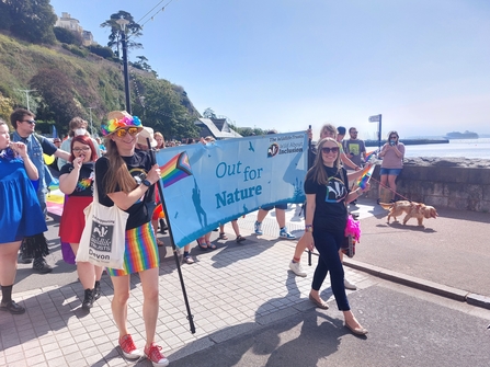 Emily holding 'out for nature' banner at Torbay pride