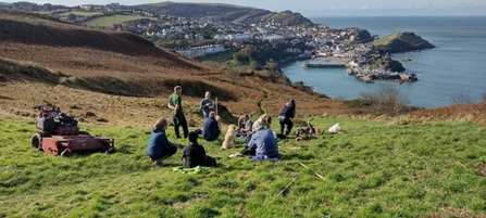 A group of people congregating together on a coastal cliff top.