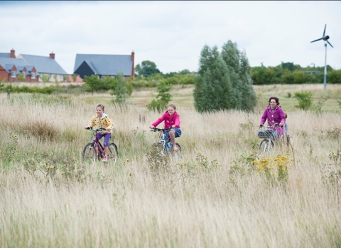 Family cycling near houses and wind turbine