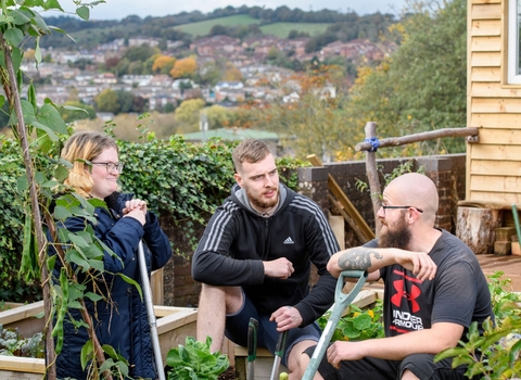 Three friends in an urban garden by a raised planter